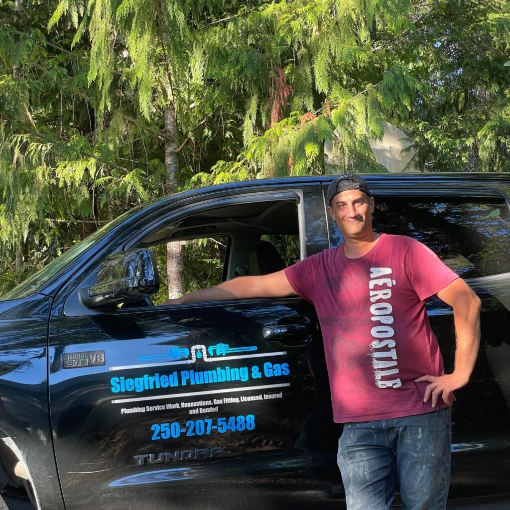 Plumbers near me. John standing next to black truck that says Siegfried Plumbing & Gas phone number on the side of the truck in blue is 250 207 5488 plumbing services near me